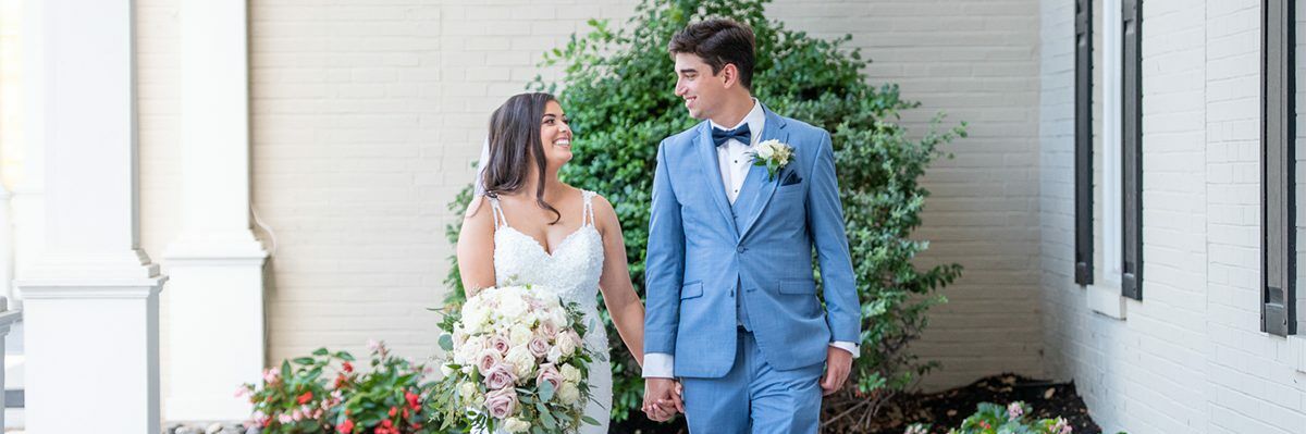 Newlywed couple standing side by side on an outside patio