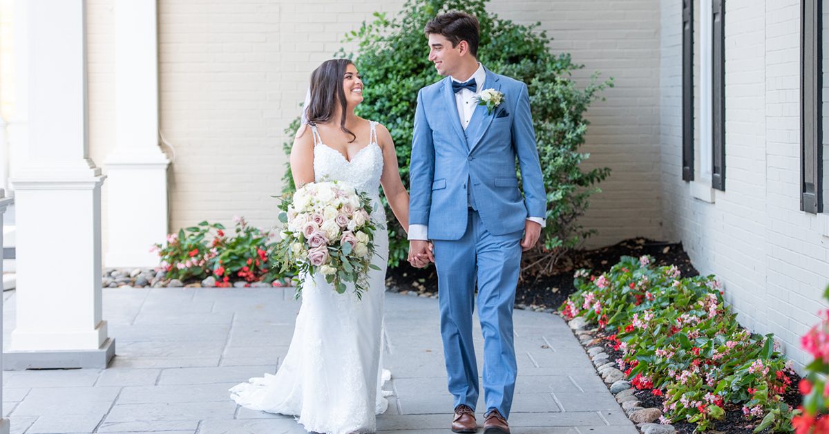 Newlywed couple standing side by side on an outside patio