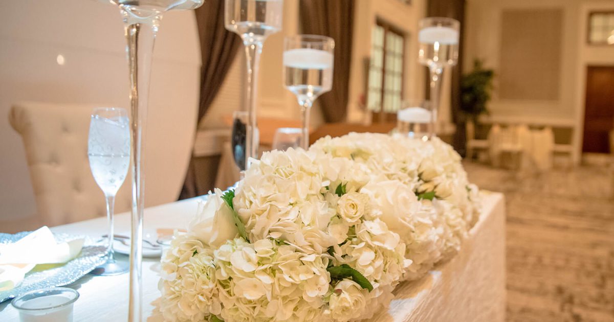 Up-close image of a wedding sweetheart table with white flowers and champagne flutes