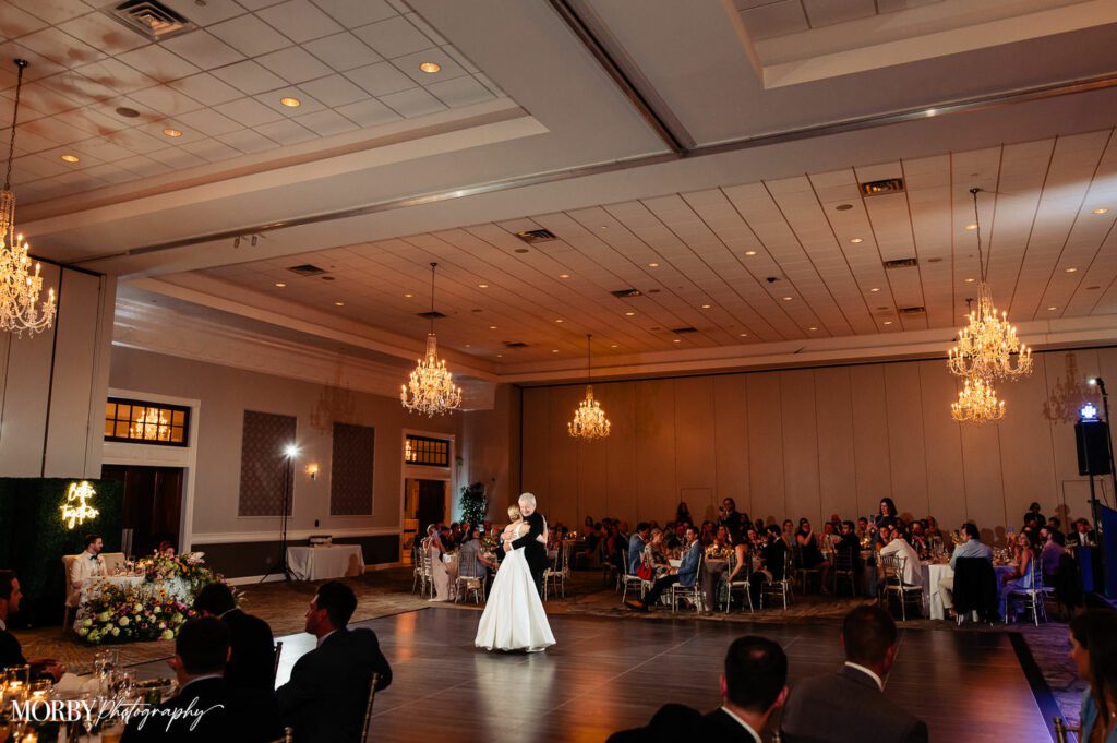 A bride and her father dancing in the center of the dance floor during a reception.